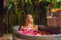 Attractive Young woman in bath with petals of tropical flowers and aroma oils. Spa treatments for skin rejuvenation