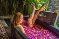 Attractive Young woman in bath with petals of tropical flowers and aroma oils. Spa treatments for skin rejuvenation