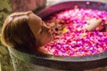 Attractive Young woman in bath with petals of tropical flowers and aroma oils. Spa treatments for skin rejuvenation