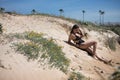 Attractive young woman in black swimsuit and sarong, solitary, relaxed and calm, lying on a beach dune. Concept tranquility, peace Royalty Free Stock Photo