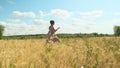 attractive young woman in brown dress runs across yellow field against blue sky with clouds. beauty lady is in hurry to