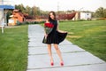 Attractive young woman with brown hair in little black dress posing, smiling and holding a bouquet of red roses Royalty Free Stock Photo