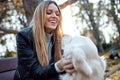 Attractive young woman caring and playing with her beautiful golden retriever dog while sitting on bench in the park Royalty Free Stock Photo