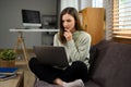 Attractive young woman in casual clothes suing laptop sitting on couch at home