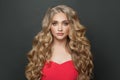 Attractive young woman celebrity with makeup and blonde curly hairstyle in red evening dress on black background Royalty Free Stock Photo