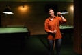 Attractive young woman chalking billiard cue while standing near pool table