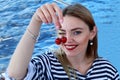Attractive young woman coquettish eats cherry. dressed in a sailor suit. Sunny day. Royalty Free Stock Photo