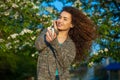 An attractive young woman with curly hair listening to music on your phone and smiling