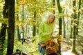 Attractive young woman cycle in autumnal forest park and makes a bouquet of autumn flowers. Dreamy hipster girl with Royalty Free Stock Photo