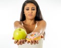 Attractive young woman on a diet deciding between an apple and a doughnut Royalty Free Stock Photo