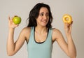 Attractive young woman on a diet deciding between an apple and a doughnut Royalty Free Stock Photo