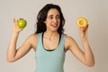 Attractive young woman on a diet deciding between an apple and a doughnut Royalty Free Stock Photo