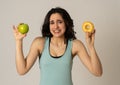 Attractive young woman on a diet deciding between an apple and a doughnut Royalty Free Stock Photo