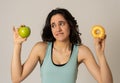 Attractive young woman on a diet deciding between an apple and a doughnut Royalty Free Stock Photo