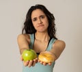 Attractive young woman on a diet deciding between an apple and a doughnut Royalty Free Stock Photo