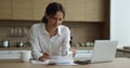 Woman do accountancy job sit in domestic kitchen at home