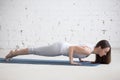 Attractive young woman doing Chaturanga Dandasana pose in white