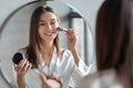 Attractive Young Woman Doing Daily Makeup While Standing Near Mirror In Bathroom Royalty Free Stock Photo