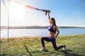 Attractive young  woman  doing TRX training outdoors near the lake at daytime. Healthy lifestyle Royalty Free Stock Photo