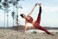 An attractive young woman doing a yoga pose for balance and stretching near the lake high in the mountains Royalty Free Stock Photo