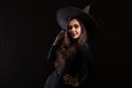 Attractive young woman dressedup like a witch for halloween with a big hat smiling