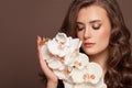 Attractive young woman face with healthy clear skin and white orchid flowers. Facial treatment and skin care concept Royalty Free Stock Photo