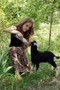 Attractive young woman is feeding a baby goat with milk from the Royalty Free Stock Photo