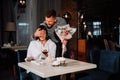 Attractive young woman getting a flowers from her boyfriend while sitting in the cafe Royalty Free Stock Photo