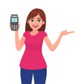 Attractive young woman/girl showing pos terminal or credit/debit cards swiping machine and gesture hand to copy space side away. Royalty Free Stock Photo