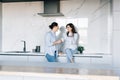 Attractive young woman and handsome man are enjoying spending time together while standing on light modern kitchen with cup of Royalty Free Stock Photo