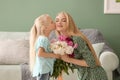 Attractive young woman and her cute little daughter with beautiful flowers at home Royalty Free Stock Photo