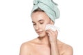 Attractive young woman with her hair wrapped in a towel, removing make up. Pretty girl with perfect complexion cleansing her face. Royalty Free Stock Photo