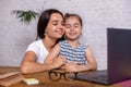 Attractive young woman and her little cute daughter are sitting at the table and having fun while doing homework Royalty Free Stock Photo