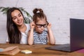 Attractive young woman and her little cute daughter are sitting at the table and having fun while doing homework Royalty Free Stock Photo