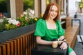 Attractive young woman holding mobile phone sitting at table with coffee cup in outdoor cafe terrace in sunny summer day Royalty Free Stock Photo