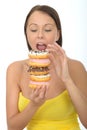 Attractive Young Woman Holding a Pile of Iced donuts