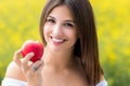 Attractive young woman holding red apple outdoors. Royalty Free Stock Photo
