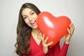 Attractive young woman holding red heart air balloon on gray background. Valentine`s Day concept. Royalty Free Stock Photo