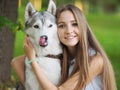 Attractive young woman hugs funny siberian husky dog with brown eyes