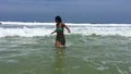 Attractive young woman jumping and playing on the waves in the ocean