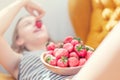 Attractive young woman laying on sofa in a home family room living room, eating fresh strawberry. Royalty Free Stock Photo