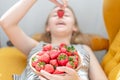 Attractive young woman laying on sofa in a home family room living room, eating fresh strawberry. Royalty Free Stock Photo
