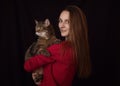 Attractive young woman with long hair with huge brown marble tabby male cat with green-yellow eyes in her arms