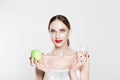 Attractive young woman looking at camera, holding in her hands green apple and glass of water promoting healthy lifestyle, diet Royalty Free Stock Photo