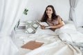 An attractive young woman is lying in bed on pillows and reading a book. A smiling curly-haired female is resting on the sofa in Royalty Free Stock Photo