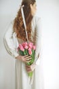 Attractive young woman in natural fabric dress holding a bouquet of tulips, isolated on white background. Royalty Free Stock Photo