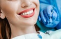 Attractive young woman with natural white teeth in dental clinic. Hands doctor dentist with medical tools. Healthy teeth concept