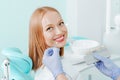 Attractive young woman with natural white teeth in dental clinic. Hands doctor dentist with teeth color palette next by face. Royalty Free Stock Photo