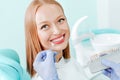 Attractive young woman with natural white teeth in dental clinic. Hands doctor dentist with teeth color palette next by face. Royalty Free Stock Photo