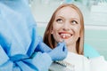 Attractive young woman with natural white teeth in dental clinic. Hands doctor dentist with teeth color palette next by face. Royalty Free Stock Photo